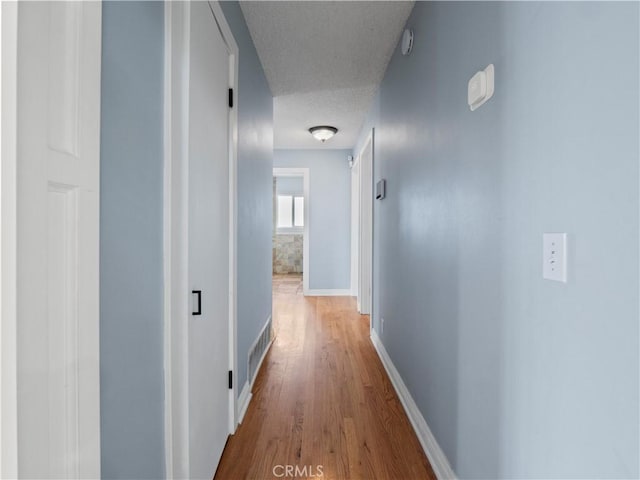 hallway with hardwood / wood-style floors and a textured ceiling