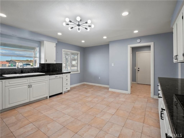 kitchen featuring white cabinetry, sink, decorative backsplash, dark stone counters, and white dishwasher