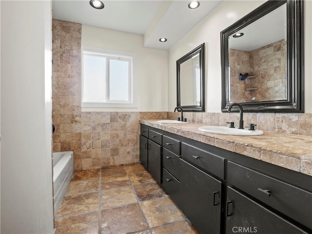 bathroom featuring tile walls, vanity, and washtub / shower combination