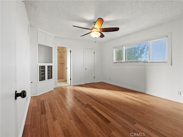 empty room featuring ceiling fan, light hardwood / wood-style floors, and a textured ceiling