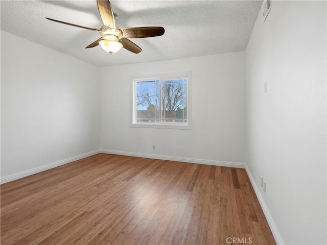 empty room with ceiling fan, wood-type flooring, and a textured ceiling