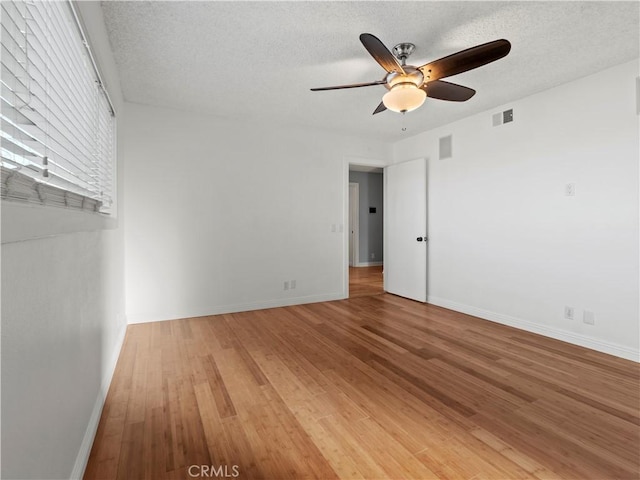 unfurnished room featuring hardwood / wood-style flooring, ceiling fan, and a textured ceiling