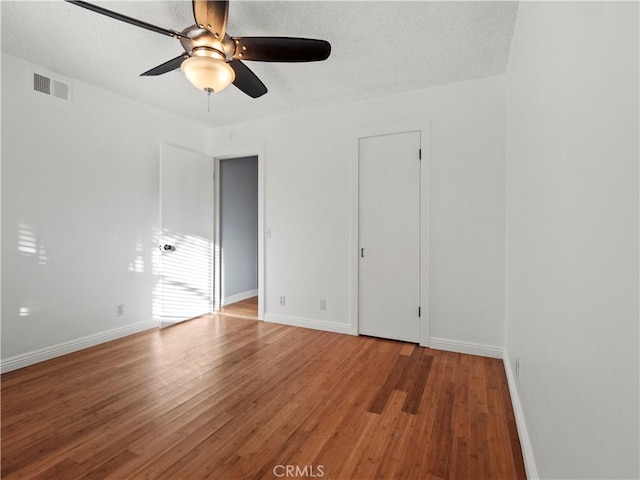 unfurnished room with ceiling fan, wood-type flooring, and a textured ceiling