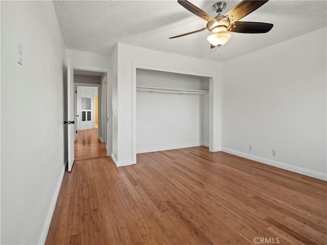 unfurnished bedroom featuring wood-type flooring, ceiling fan, a textured ceiling, and a closet