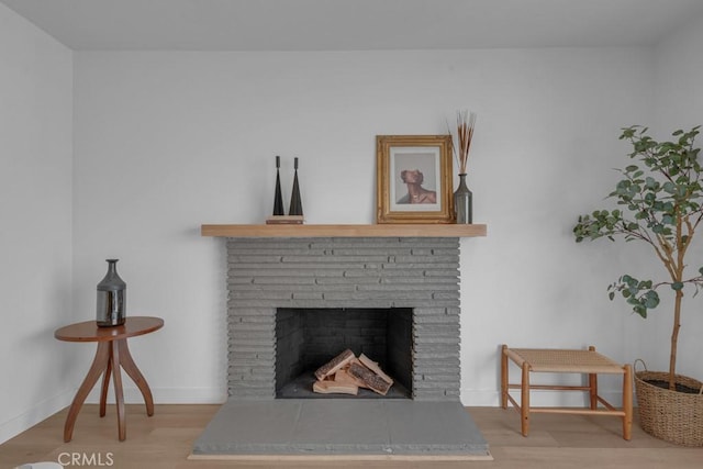 interior details featuring baseboards, a fireplace with raised hearth, and wood finished floors