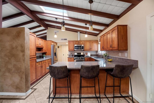 kitchen with a breakfast bar, sink, decorative light fixtures, appliances with stainless steel finishes, and kitchen peninsula