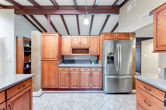 kitchen featuring lofted ceiling with beams, light tile patterned floors, stainless steel fridge, and light stone counters