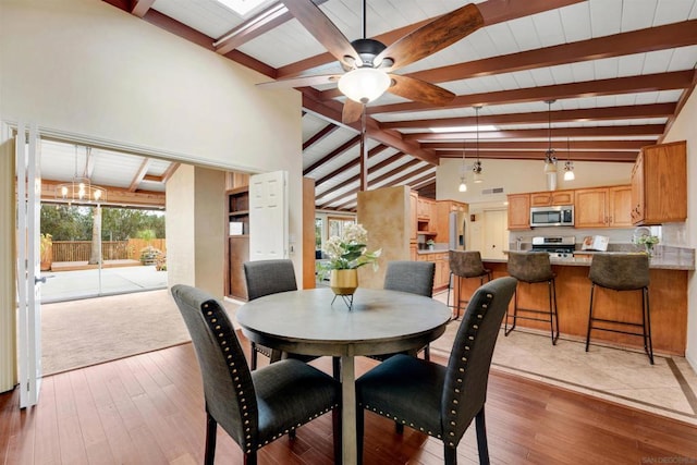 dining space featuring ceiling fan, wood-type flooring, and beam ceiling