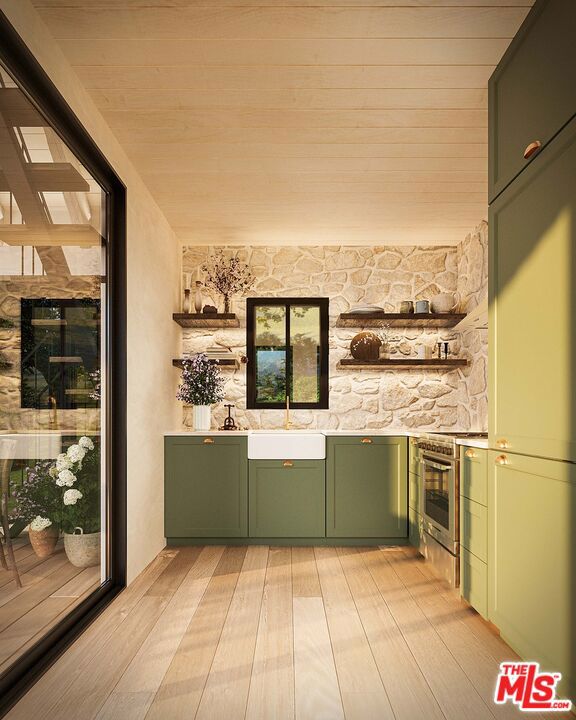 bar featuring sink, light hardwood / wood-style flooring, stainless steel range, and green cabinetry