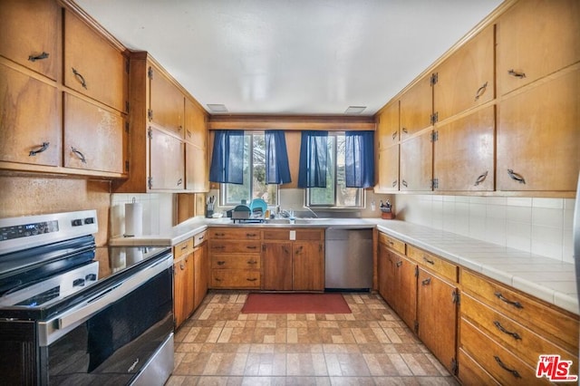 kitchen with decorative backsplash, tile counters, and stainless steel appliances