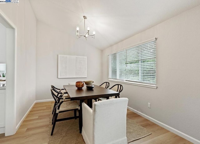 dining room featuring an inviting chandelier, lofted ceiling, and light wood-type flooring