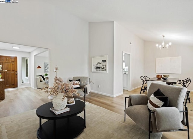 living room with a notable chandelier, high vaulted ceiling, and light wood-type flooring