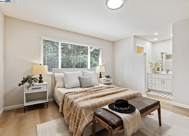 bedroom featuring ensuite bathroom and light hardwood / wood-style flooring