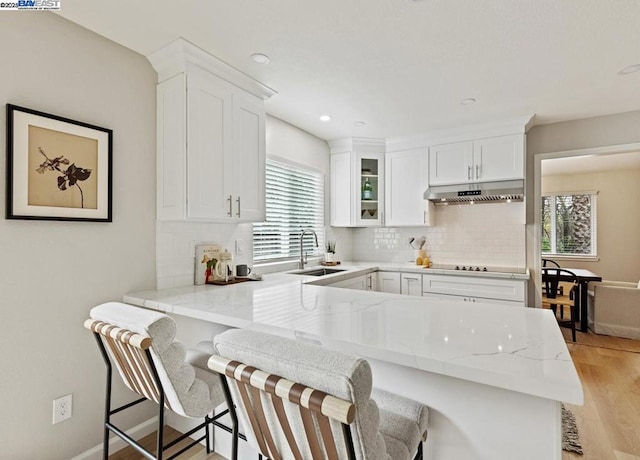 kitchen with white cabinetry, a kitchen bar, kitchen peninsula, and sink