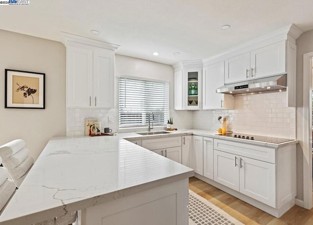 kitchen with white cabinetry, sink, black electric cooktop, and kitchen peninsula