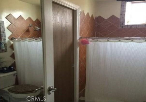 bathroom with curtained shower and toilet