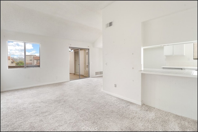 spare room featuring light carpet, vaulted ceiling, and a textured ceiling