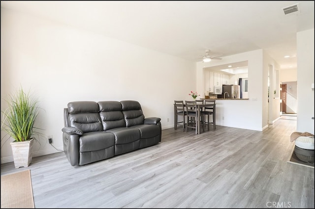 living room with ceiling fan and light wood-type flooring