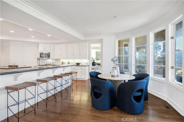 dining room with dark hardwood / wood-style flooring, ornamental molding, and a raised ceiling