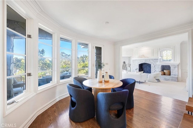 dining room featuring dark hardwood / wood-style flooring, ornamental molding, and a fireplace