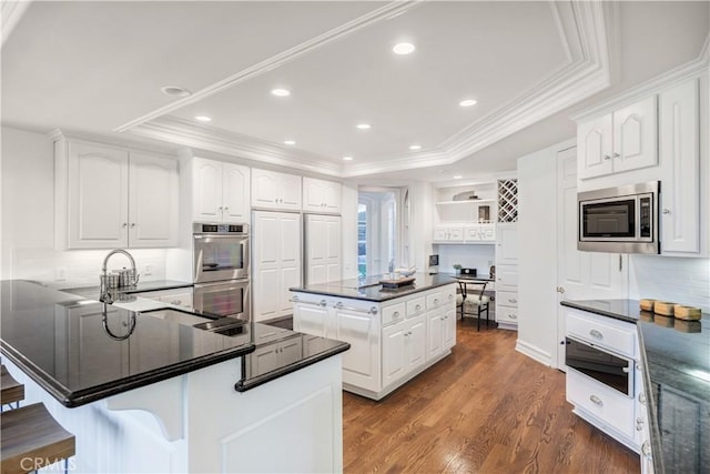 kitchen featuring white cabinetry, appliances with stainless steel finishes, a tray ceiling, and a kitchen island