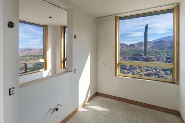 spare room with a mountain view, a wealth of natural light, and concrete floors