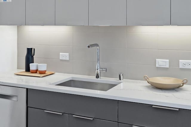 kitchen featuring sink, gray cabinetry, light stone countertops, decorative backsplash, and stainless steel dishwasher