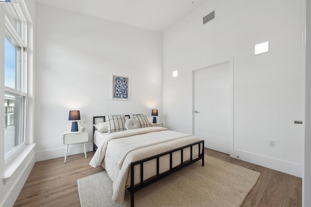 bedroom with a high ceiling and light hardwood / wood-style floors