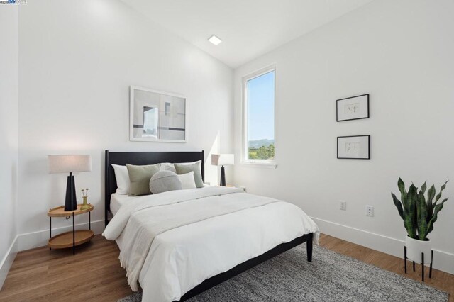 bedroom with vaulted ceiling and wood-type flooring