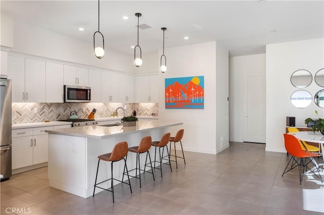 kitchen featuring appliances with stainless steel finishes, a center island, hanging light fixtures, and white cabinets