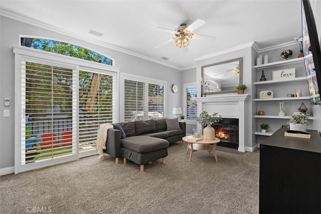 living room featuring ornamental molding, carpet flooring, ceiling fan, and a healthy amount of sunlight