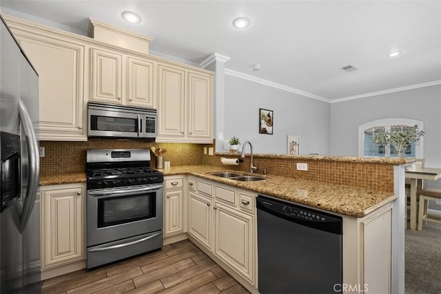 kitchen with cream cabinetry, sink, kitchen peninsula, and appliances with stainless steel finishes