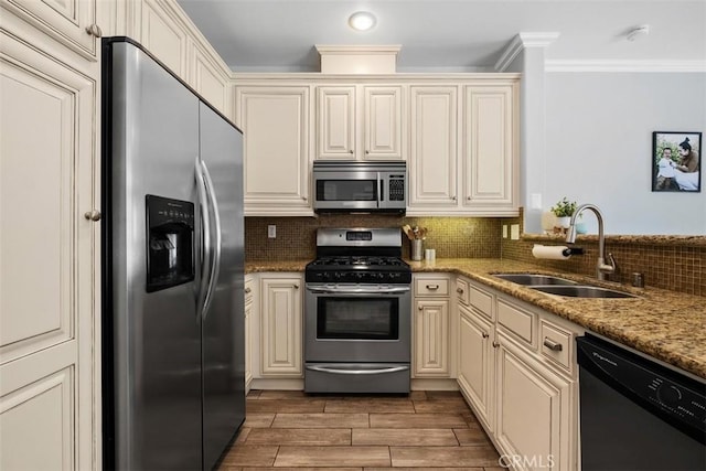 kitchen featuring sink, light stone counters, tasteful backsplash, stainless steel appliances, and cream cabinetry