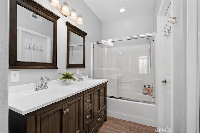 bathroom with hardwood / wood-style flooring, enclosed tub / shower combo, and vanity