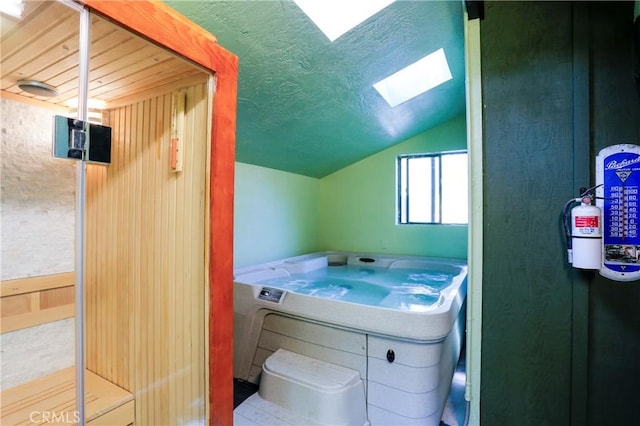 bathroom with vaulted ceiling with skylight, washer / clothes dryer, and a textured ceiling