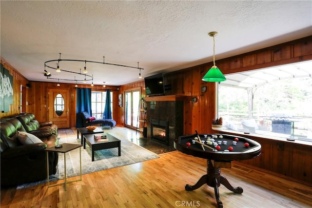 playroom with hardwood / wood-style flooring, a fireplace, a textured ceiling, and wood walls