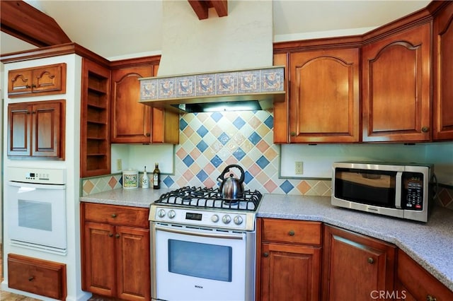 kitchen with white appliances, custom exhaust hood, light stone countertops, and decorative backsplash