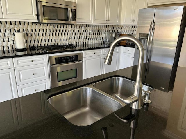 kitchen featuring sink, backsplash, white cabinets, and appliances with stainless steel finishes