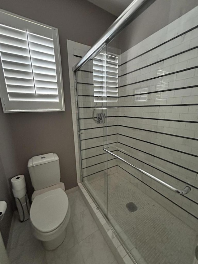 bathroom with a shower with door and toilet