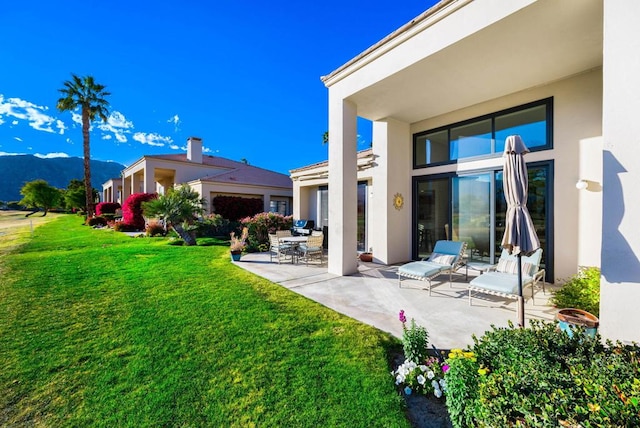 back of house featuring a patio, a mountain view, and a lawn