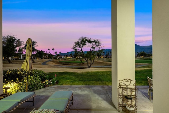 patio terrace at dusk featuring a mountain view and a lawn