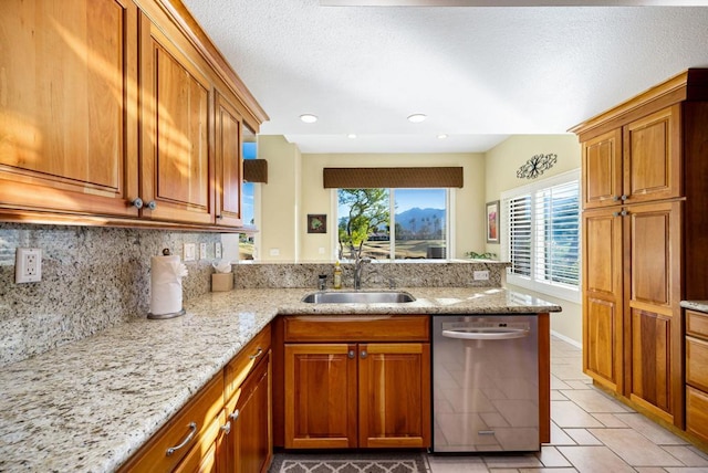 kitchen featuring dishwasher, sink, backsplash, kitchen peninsula, and light stone countertops