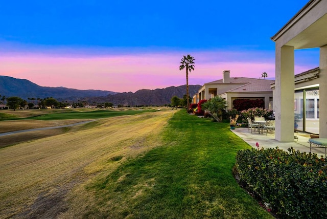 yard at dusk with a mountain view and a patio