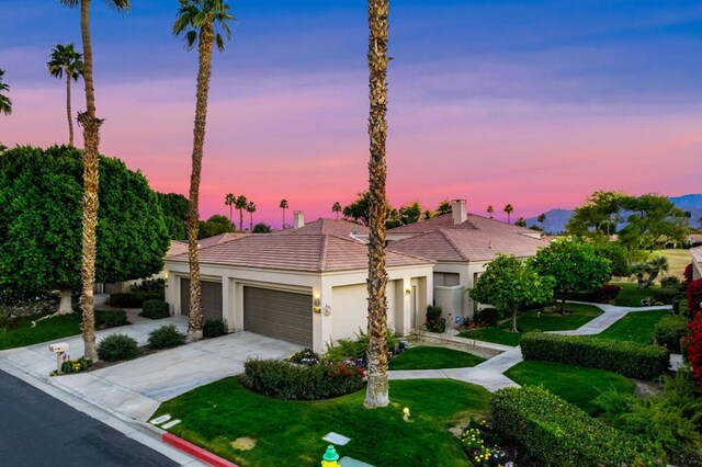 view of front of property with a garage and a lawn