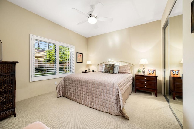 bedroom with light colored carpet, ceiling fan, and a closet