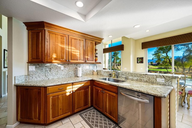 kitchen featuring light stone counters, sink, kitchen peninsula, and dishwasher