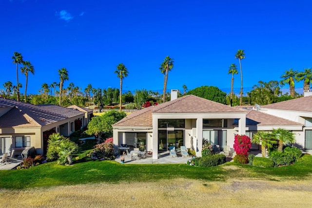 back of house with a yard and a patio