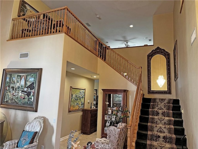 stairs featuring tile patterned flooring, a high ceiling, and ceiling fan