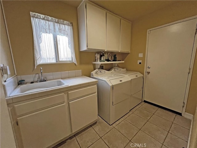 washroom featuring sink, light tile patterned floors, cabinets, and washing machine and clothes dryer