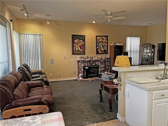 carpeted living room featuring a brick fireplace, track lighting, and ceiling fan